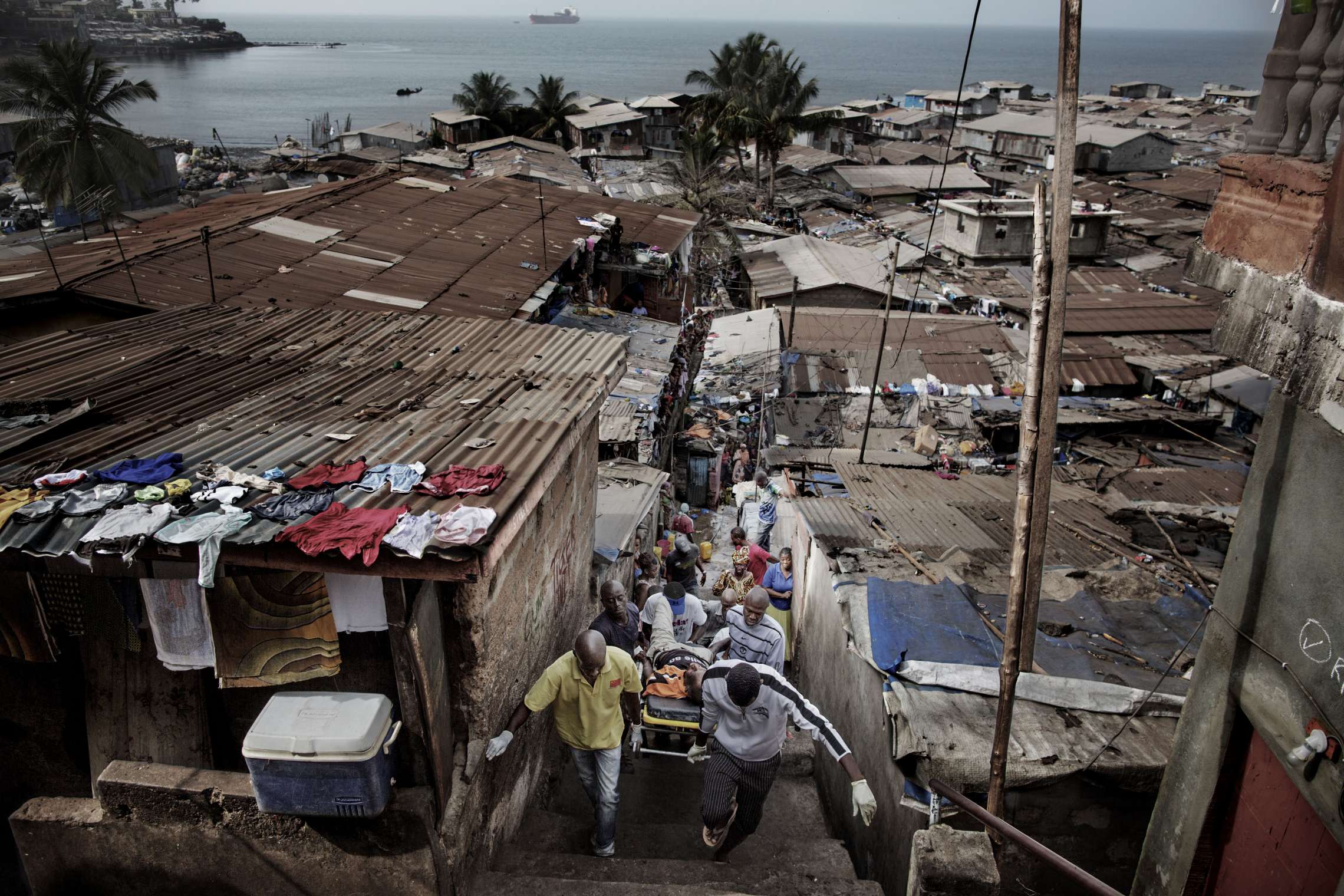 00619 2. Nyhet reportasje 21.01.2015 01/08 Ebola Et ambulanseteam bærer en mann de mistenker har ebola ut av slummen ved markedet i Freetown, Sierra Leone. Hjelpearbeidere har kjempet mot ebolaviruset siden utbruddet av det i mai 2014. Mer enn 100 helsearbeidere og 11 av Sierra Leones rundt 120 leger har omkommet. Totalt er mer enn 3.500 mennesker døde av ebola i landet i januar 2015. I løpet av året klarte man å bekjempe virsuset ved blant annet å isolere smittede landsbyer, drive helsekampanjer, stenge grenseoverganger og i siste liten kom det internasjonale samfunnet på banen med både helsehjelp og økonomisk støtte.